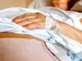 Dłoń pacjenta z wenflonem, przygotowująca się do podróży ze szpitala do hospicjum.