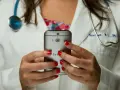 Lekarz w białym kitlu trzyma smartfon, na którym widać aparat i logo HTC.