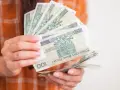 Dłonie trzymające stos banknotów 100 zł. Może to być symbol wsparcia, np. zasilek dla bezrobotnych.