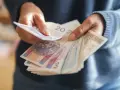 Ręce liczą banknoty, zastanawiając się, co z pieniędzmi z OFE po przejściu na emeryturę.
