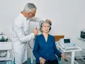Laryngolog bada słuch pacjentki za pomocą słuchawek i urządzenia.
