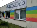 Budynek szkoły z kolorowymi pasami i napisem "SZKOŁA PODSTAWOWA ARKA NOEGO".