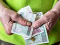 Dłonie trzymające polskie banknoty: 10, 20 i 100 złotych.