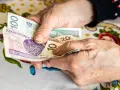 Dłonie starszej osoby liczą pieniądze. Może to być dodatek opiekuńczy po 80 roku życia, zapewniający wsparcie finansowe.