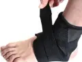 Dłoń zapina czarną ortezę na stopie i kostce.