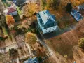 Widok z lotu ptaka na wieś z budynkami i jesiennymi drzewami pokrytymi liśćmi.