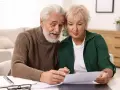Starsze małżeństwo analizuje dokumenty przy stole.