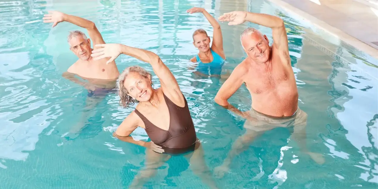 Seniorzy ćwiczą w basenie, rehabilitując kręgosłup. Takie miejsca często poleca ZUS na sanatorium.