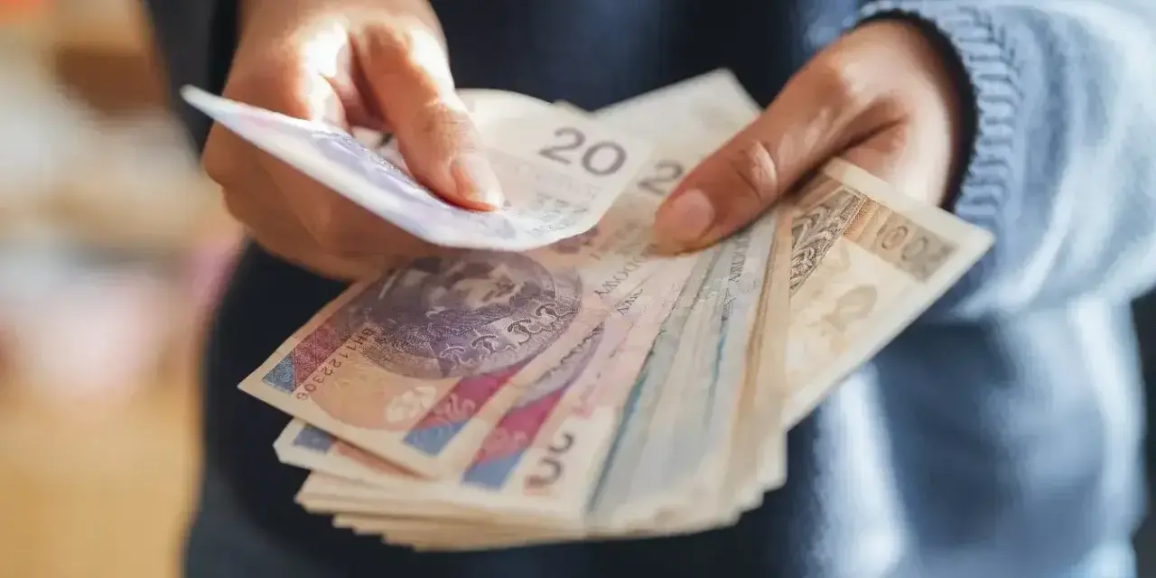 Ręce liczą banknoty, zastanawiając się, co z pieniędzmi z OFE po przejściu na emeryturę.