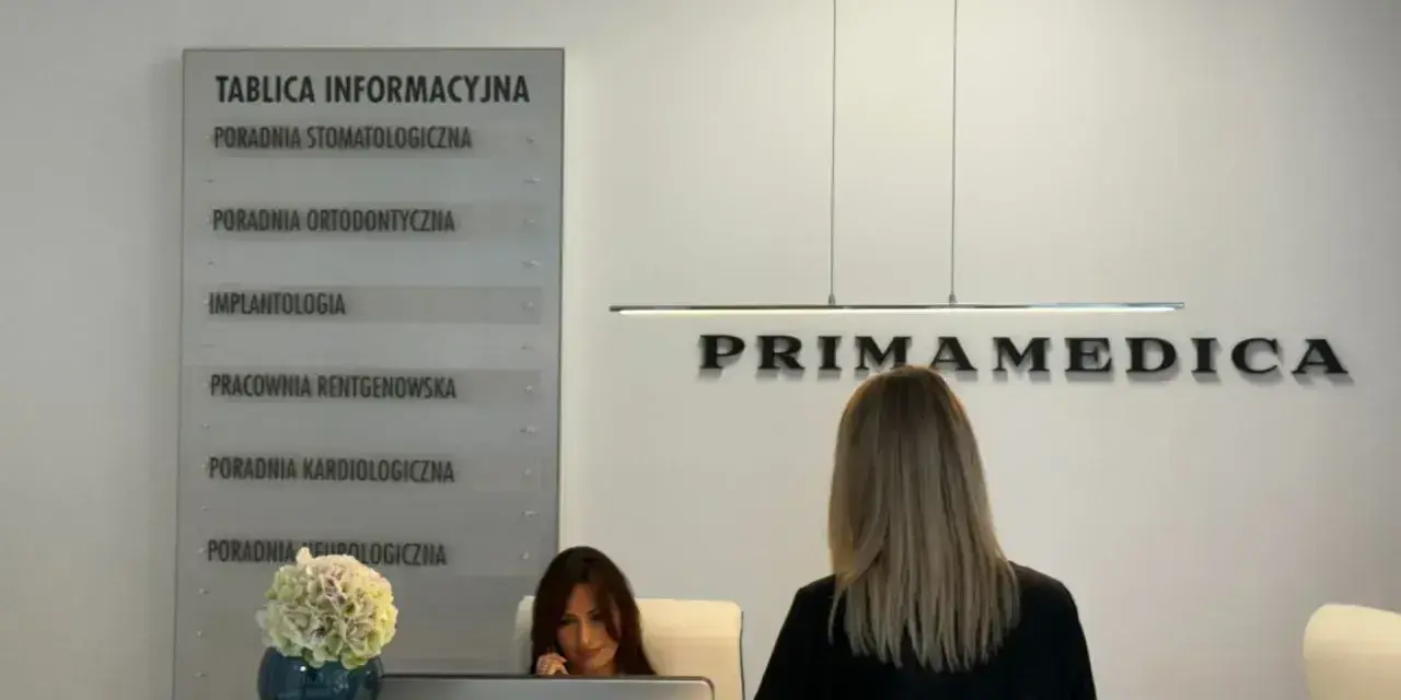 Recepcja gabinetu stomatologicznego Primamedica z tablicą informacyjną i pracownicą.