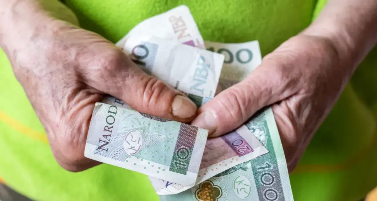 Dłonie trzymające polskie banknoty: 10, 20 i 100 złotych.