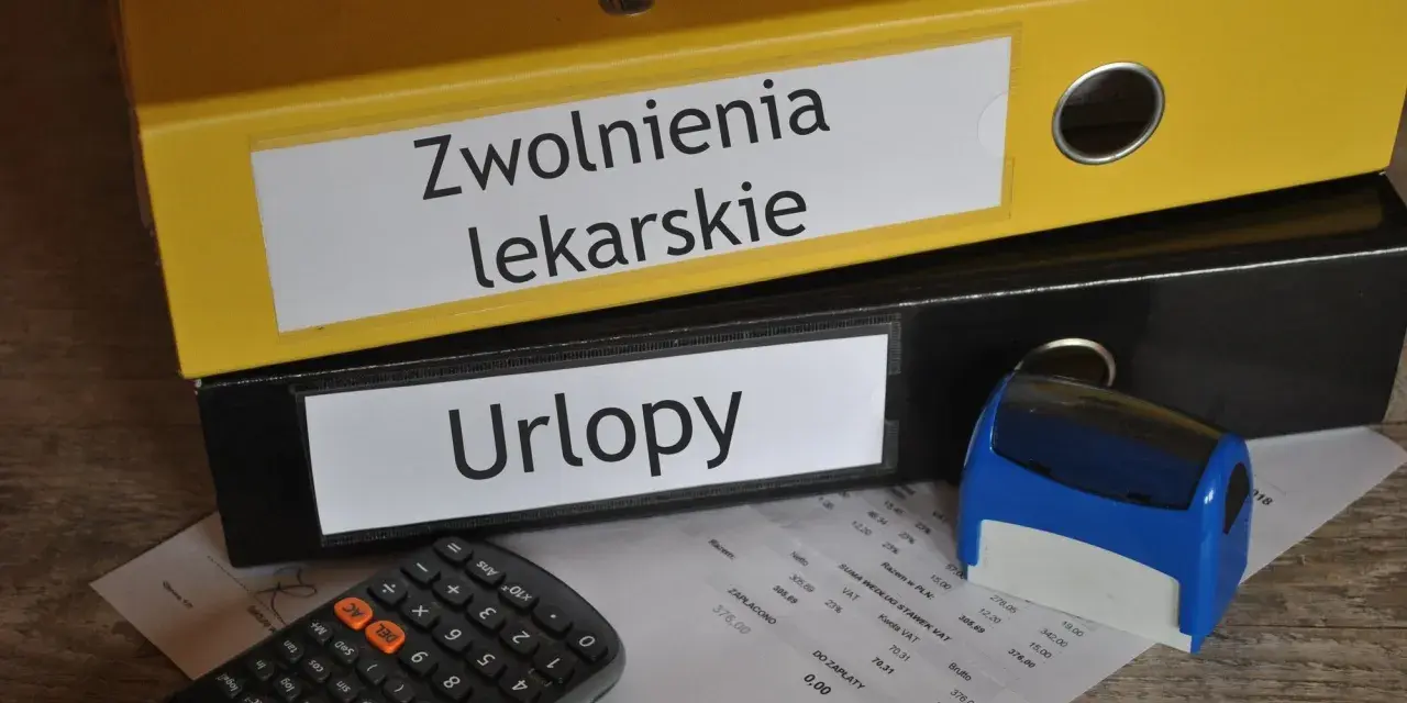 Dwa segregatory z napisami "Zwolnienia lekarskie" i "Urlopy", kalkulator, pieczątka i dokumenty.