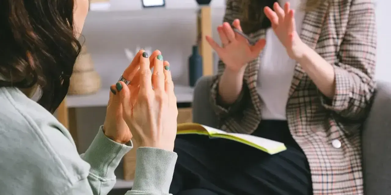 Dwie kobiety rozmawiają w gabinecie, jedna gestykuluje.