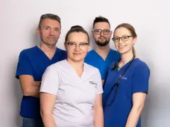 Czterech lekarzy w uniformach medycznych, uśmiechnięci, na białym tle.