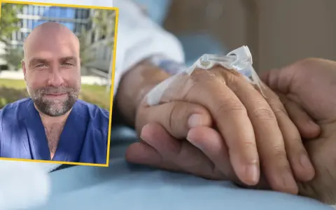 Uśmiechnięty mężczyzna w niebieskim uniformie medycznym podaje słowa otuchy choremu na raka, trzymając go za rękę z wenflonem.