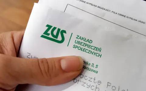 Dłoń trzyma dokument z logo ZUS i napisem "Zakład Ubezpieczeń Społecznych".