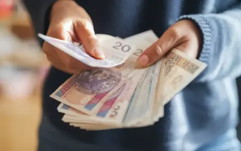 Ręce liczą banknoty, zastanawiając się, co z pieniędzmi z OFE po przejściu na emeryturę.