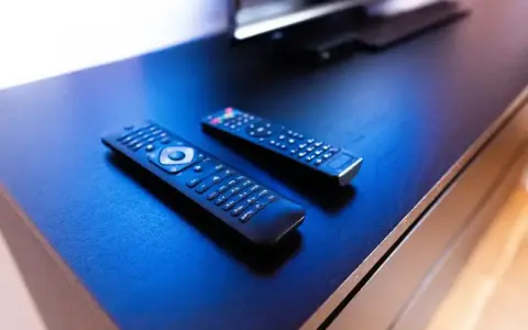 Dwa piloty leżą na czarnym blacie. Jeden z nich ma przycisk "Subtitle", który może pomóc w rozwiązaniu problemu, jak wyłączyć napisy dla niesłyszących na Samsungu.