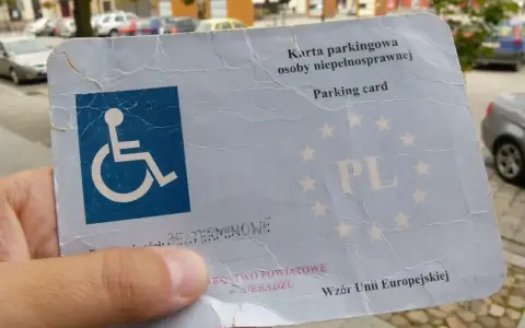 Karta parkingowa dla niepełnosprawnych, z symbolem wózka inwalidzkiego i oznaczeniem PL. Ułatwia parkowanie w mieście.