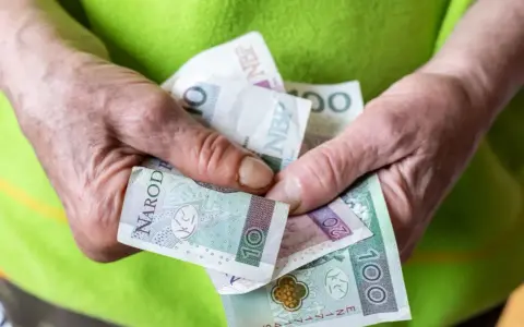 Dłonie trzymające polskie banknoty: 10, 20 i 100 złotych.