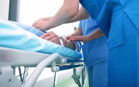 Pacjent na łóżku szpitalnym, pielęgniarki przy kroplówce. Czy to początek drogi do pokonania choroby a?
