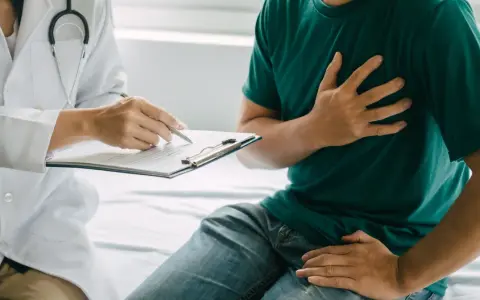 Lekarz spisuje dokumentację pacjentowi, który skarży się na ból w klatce piersiowej, co może wpłynąć na jego renta chorobowa.