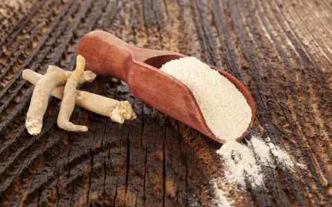 Korzeń i proszek ashwagandhy na drewnianym tle.
