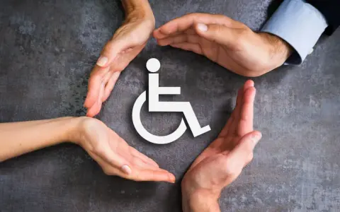 Symbol wózka inwalidzkiego otoczony dłońmi symbolizującymi wsparcie i opiekę.