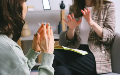 Dwie kobiety rozmawiają w gabinecie, jedna gestykuluje.