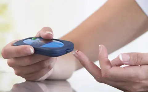 Osoba mierzy poziom glukozy glukometrem, co jest kluczowe w monitorowaniu cukrzycy typu 3.