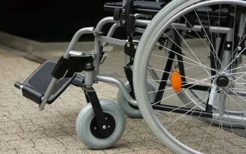 Zbliżenie na wózek inwalidzki z widocznymi kołami i podnóżkiem.