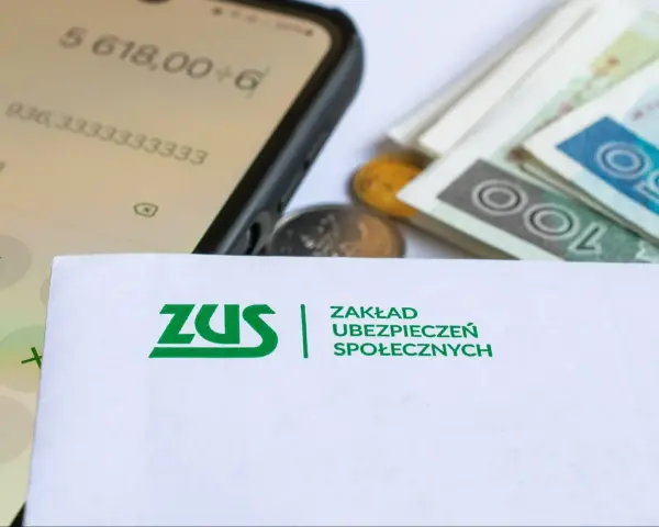ZUS, pieniądze, monety i kalkulator na ekranie telefonu.