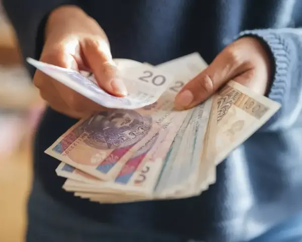 Ręce liczą banknoty, zastanawiając się, co z pieniędzmi z OFE po przejściu na emeryturę.