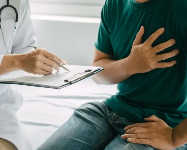 Lekarz spisuje dokumentację pacjentowi, który skarży się na ból w klatce piersiowej, co może wpłynąć na jego renta chorobowa.