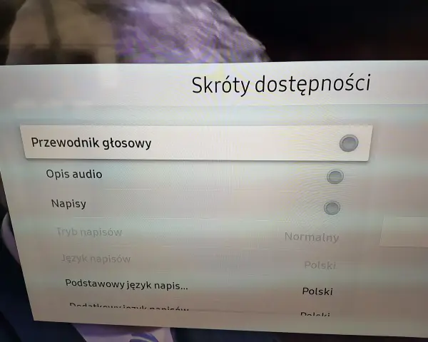 Menu telewizora z opcjami "Przewodnik głosowy", "Opis audio", "Napisy", "Tryb napisów", "Język napisów".