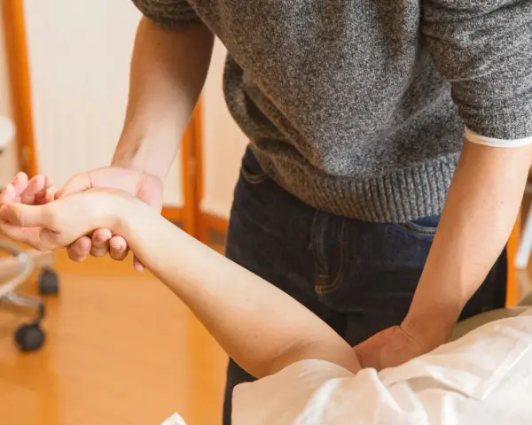 Fizjoterapeuta masuje przedramię pacjenta.