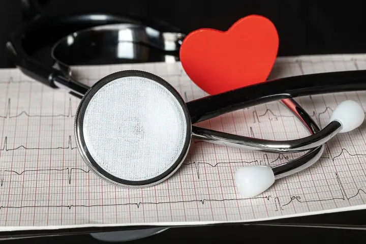 Stetoskop i czerwone serce na tle EKG.