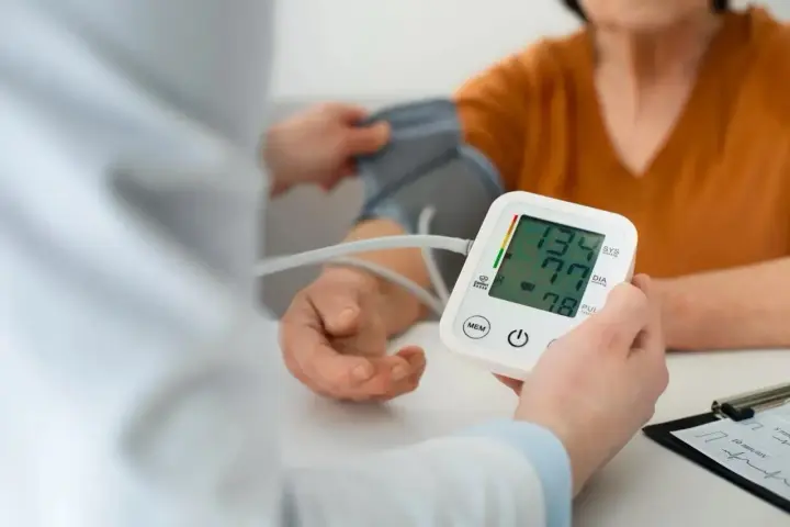 Pomiar ciśnienia krwi. Na ekranie aparatu widnieje wynik 134/77, a poniżej 78.