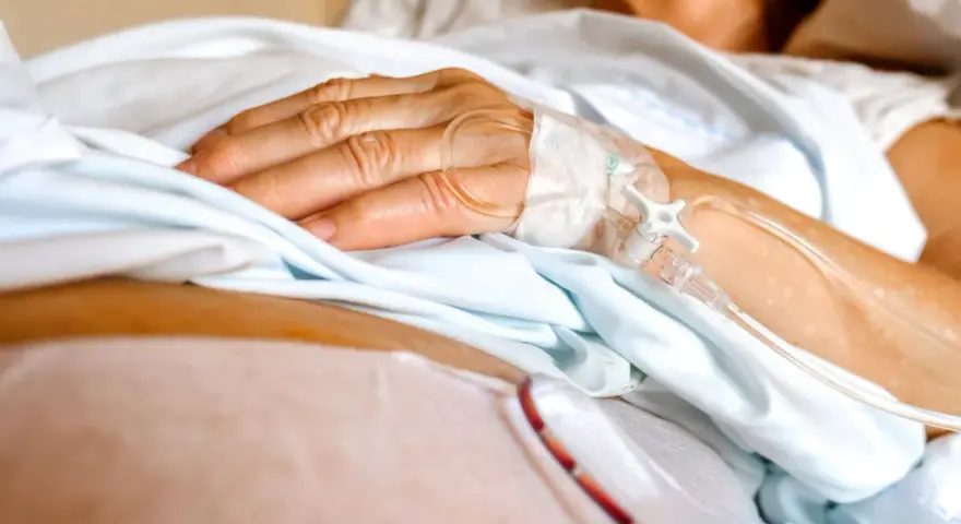 Dłoń pacjenta z wenflonem, przygotowująca się do podróży ze szpitala do hospicjum.