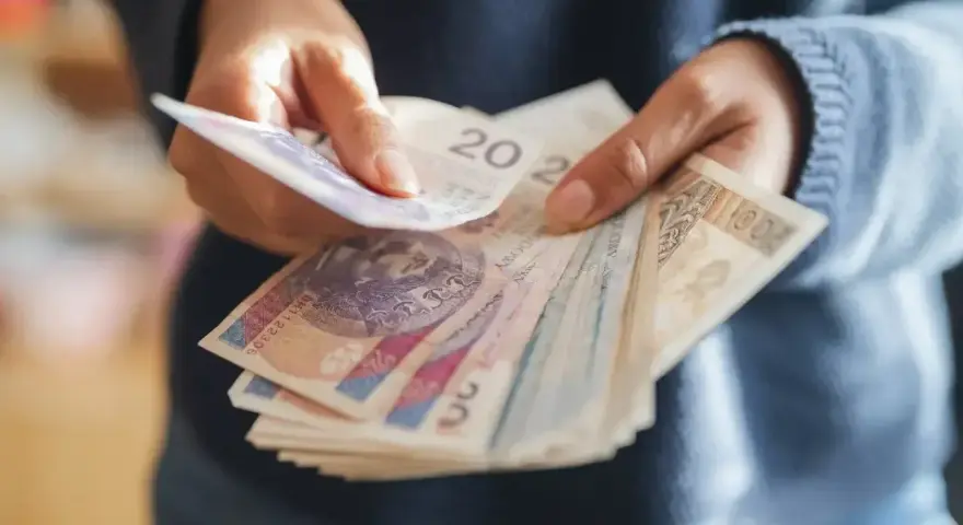 Ręce liczą banknoty, zastanawiając się, co z pieniędzmi z OFE po przejściu na emeryturę.