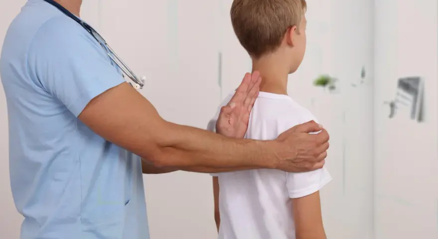Lekarz bada chłopca, sprawdzając jego postawę. Może to być część diagnostyki zespołu Marfana objawy.