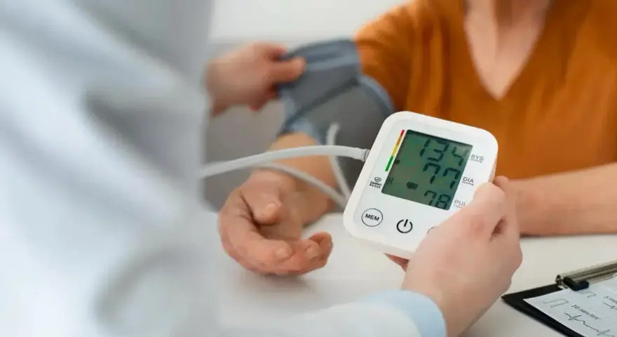 Pomiar ciśnienia krwi. Na ekranie aparatu widnieje wynik 134/77, a poniżej 78.