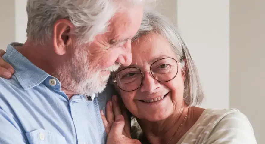 Uśmiechnięta para seniorów, która cieszy się życiem i przywilejami po 75 roku życia. Ich miłość kwitnie.